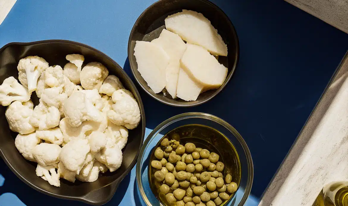 Zutaten für eine Fischpfanne mit Rotzungenfilets, Blumenkohl, Oliven und Kapern auf der Arbeitsfläche