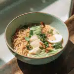 Kokos-Curry-Ramen mit Seelachs, Garnelen, Spinat, Koriander und Röstzwiebeln in einer Suppenschale