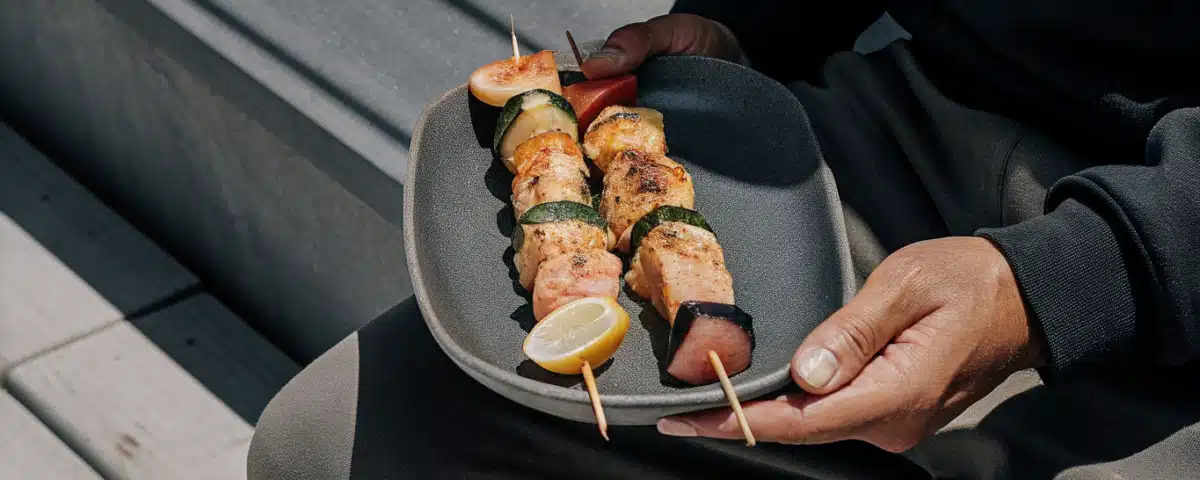 Gegrillte Fischspieße mit Lachs, Kabeljau, Garnelen und Gemüse auf einem Teller mit Zitronenspalten