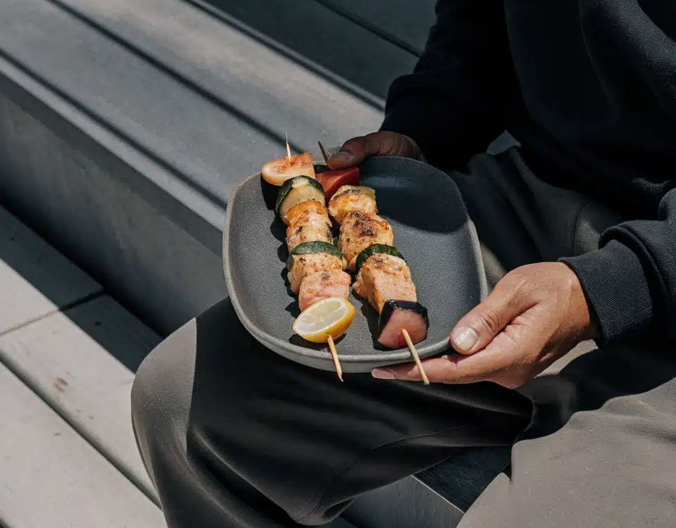 Gegrillte Fischspieße mit Lachs, Kabeljau, Garnelen und Gemüse auf einem Teller mit Zitronenspalten